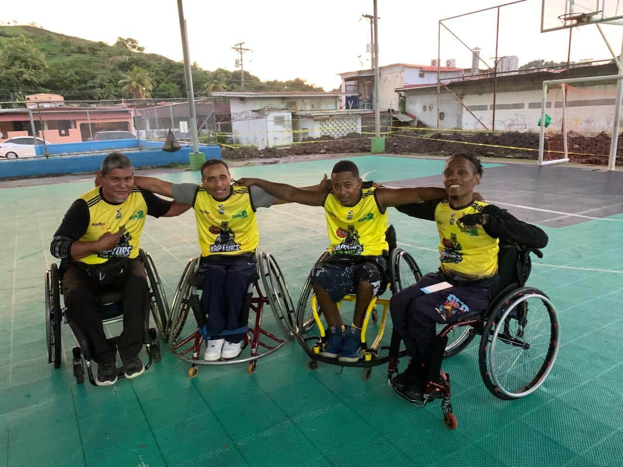 Cuatro jugadores de baloncesto sobre ruedas, con los brazos enlazados, en la cancha