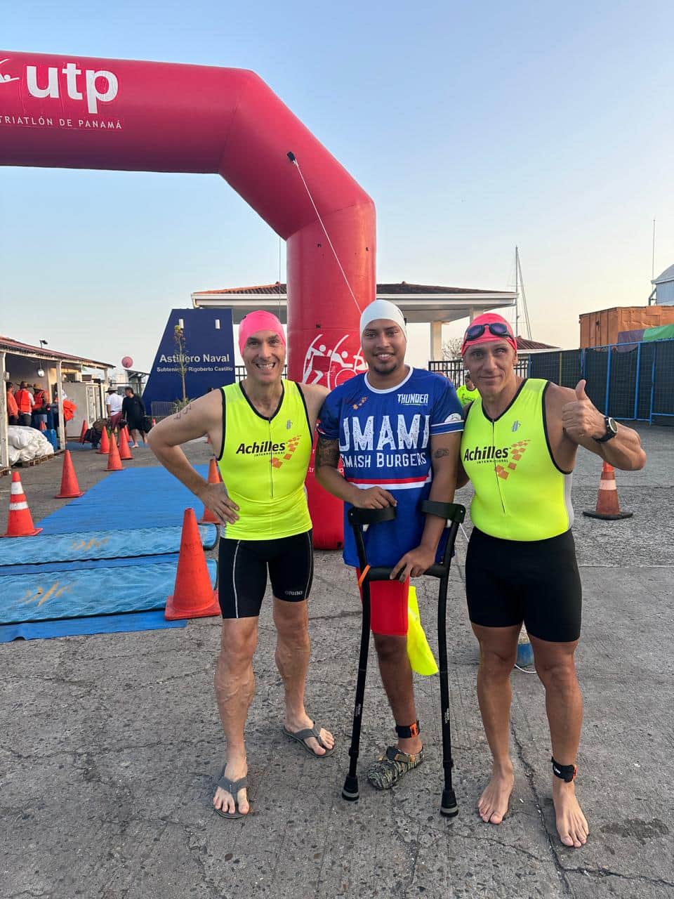 Tres triatletas posan junto al arco de meta al terminar la competencia